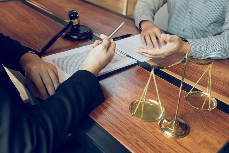 Redford lawyer reviewing personalized case strategies with a client at a law firm office desk.