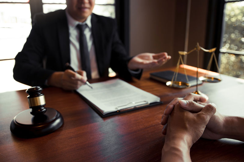 Clawson lawyer reviewing personalized case strategies with a client at a law firm office desk.