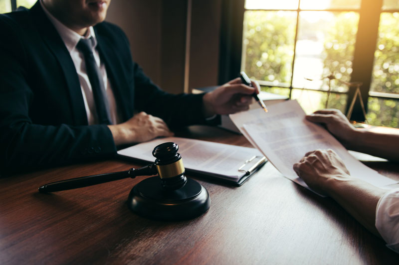 Farmington Hills lawyer reviewing personalized case strategies with a client at a law firm office desk.