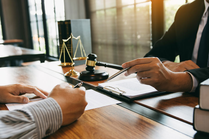 Royal Oak lawyer reviewing personalized case strategies with a client at a law firm office desk.