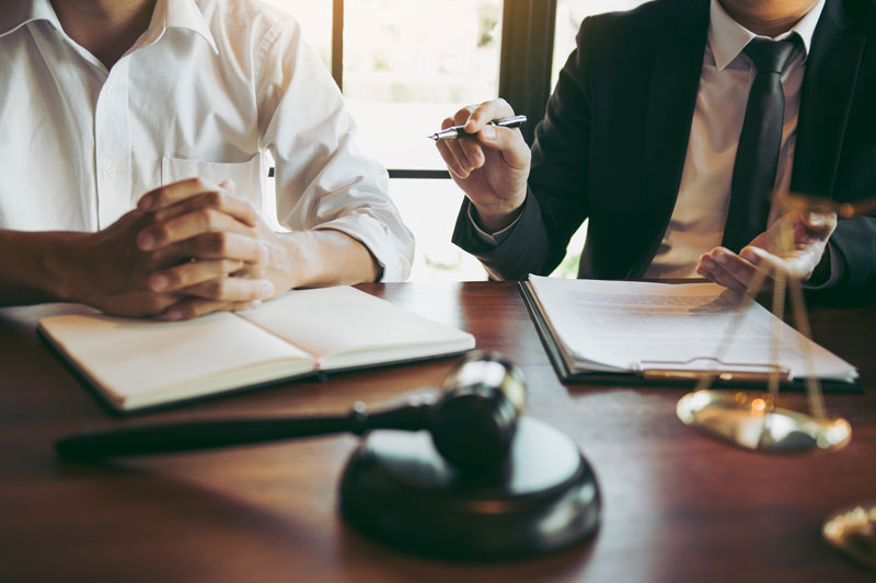 Livonia lawyer reviewing personalized case strategies with a client at a law firm office desk.