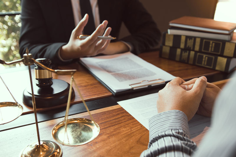 Madison Heights lawyer reviewing personalized case strategies with a client at a law firm office desk.