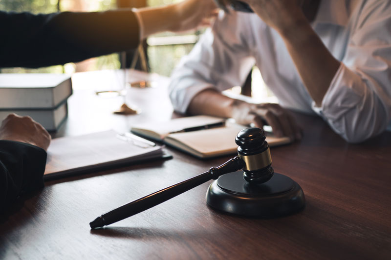 Troy lawyer reviewing personalized case strategies with a client at a law firm office desk.