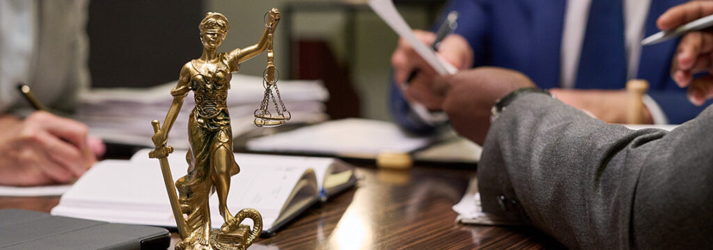 Lawyers at Hadd Law examining legal paperwork beside a Lady Justice statue covering various practice areas.